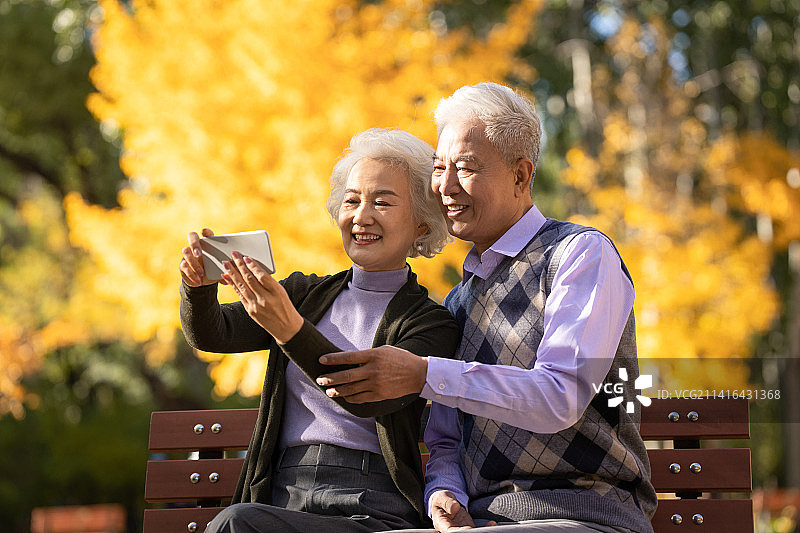老年夫妇使用手机拍照图片素材