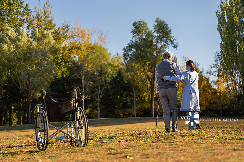 户外护士搀扶老年人散步的背影图片素材