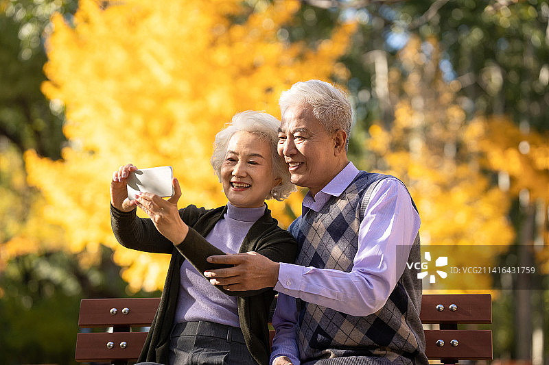 老年夫妇使用手机拍照图片素材
