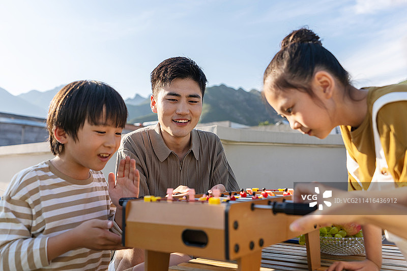 青年父亲和孩子在户外玩桌上足球图片素材