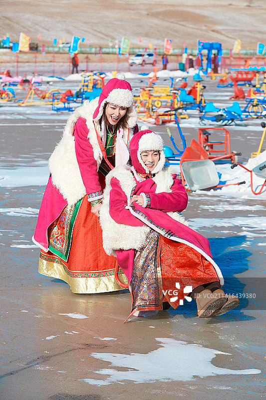 冬天在冻结湖面玩嬉戏滑冰的闺蜜少女图片素材