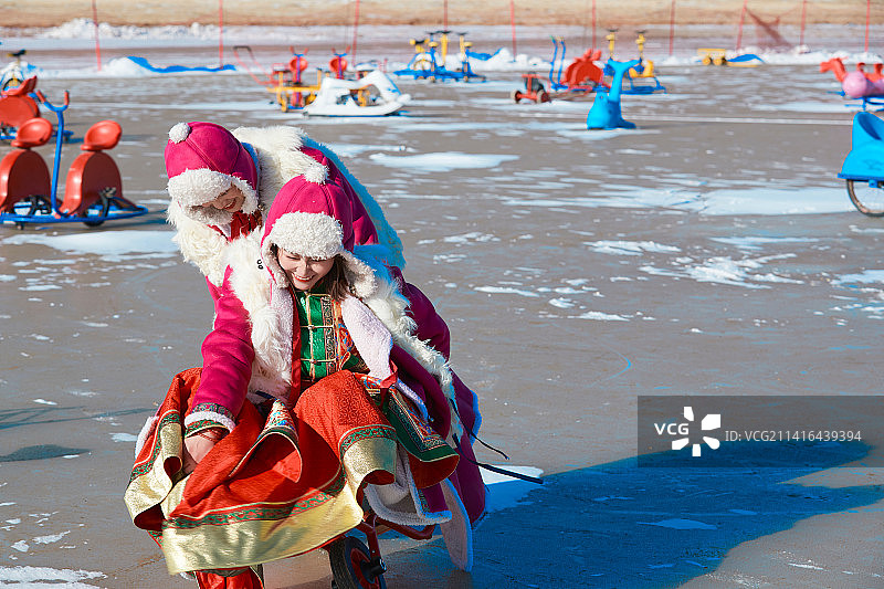 冬天在冻结湖面玩嬉戏滑冰的闺蜜少女图片素材