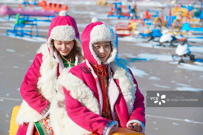 冬天在冻结湖面玩嬉戏滑冰的闺蜜少女图片素材