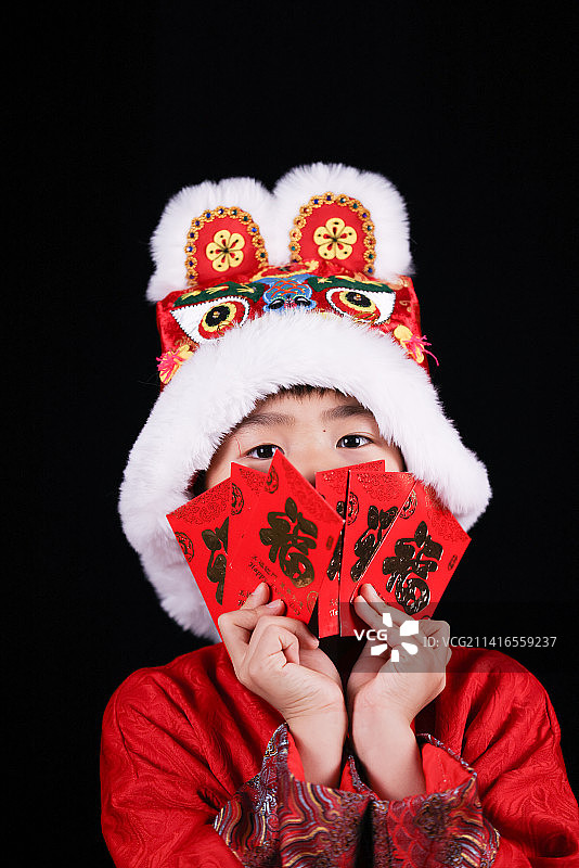 带虎头帽的中国小男孩和新年红包图片素材