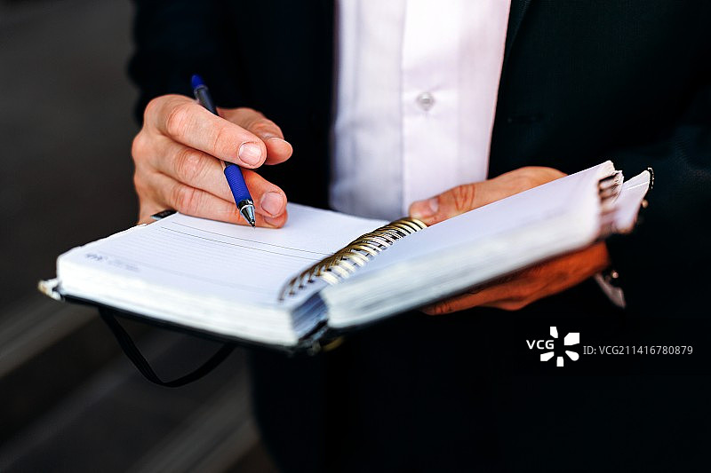 男性手部特写：用笔在笔记本上写笔记图片素材