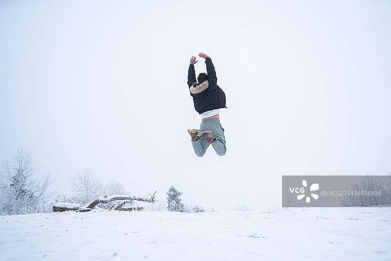 冬季雪地里跳跃的少年背影图片素材