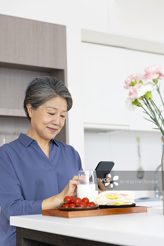 老年女子吃早餐、使用手机图片素材