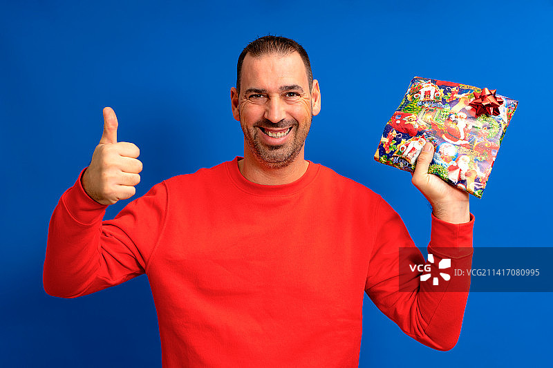 快乐的男人拿着礼物，竖起大拇指图片素材