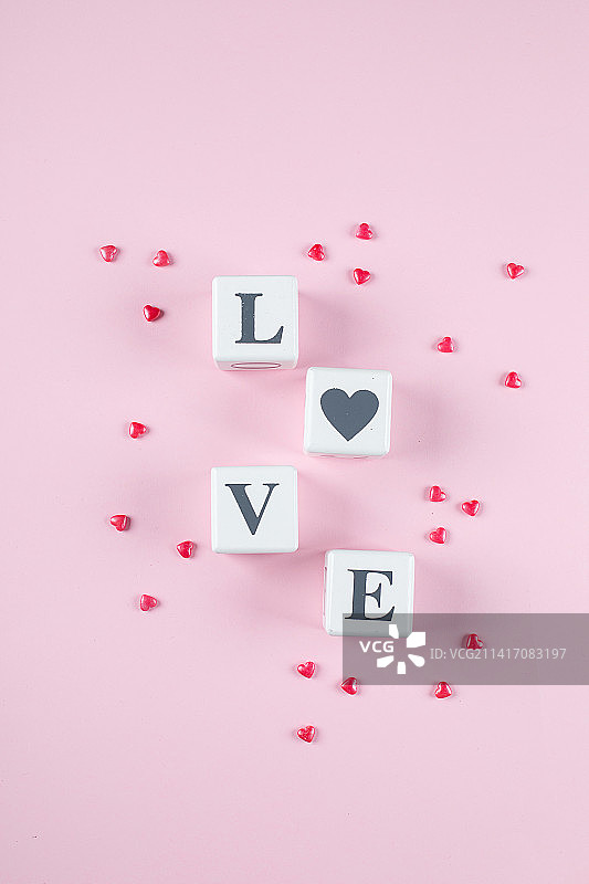 在粉红色糖果心背景上的白色木块中写下的爱情信息，平放，顶视图，哈萨克斯坦图片素材