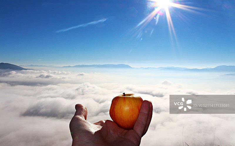 手持苹果，背景为波黑天空图片素材