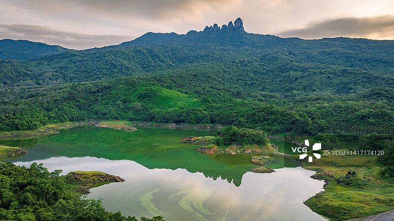 日出时分的七仙岭七指岭倒影在水库平静的水面上，天边显示出温暖的金黄色图片素材