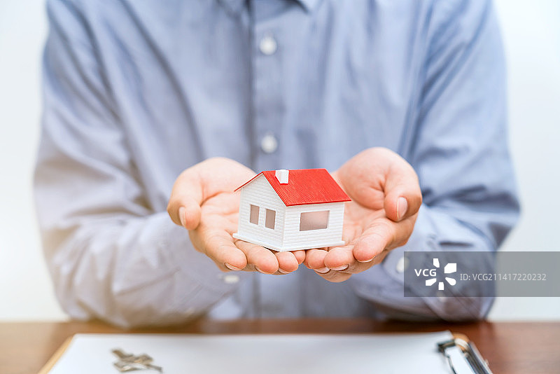 房地产经纪人手捧房子模型——房地产销售概念图片素材