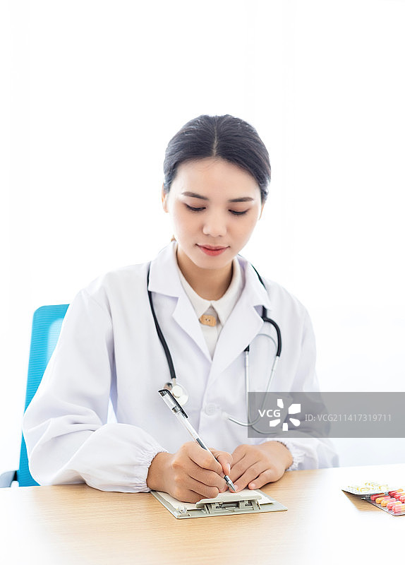 一名中国女医生坐在拿着本子和笔在做记录图片素材
