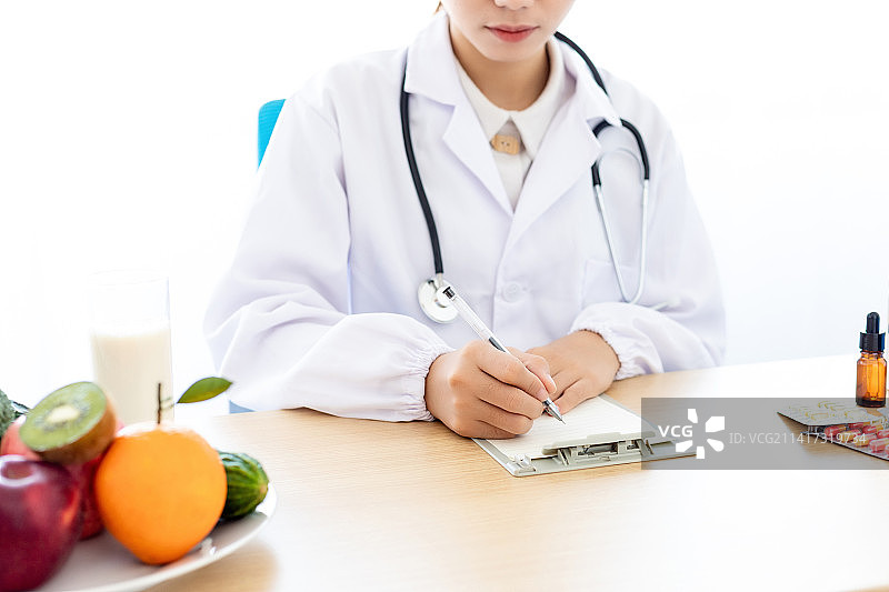 一名中国女医生在用笔做记录图片素材