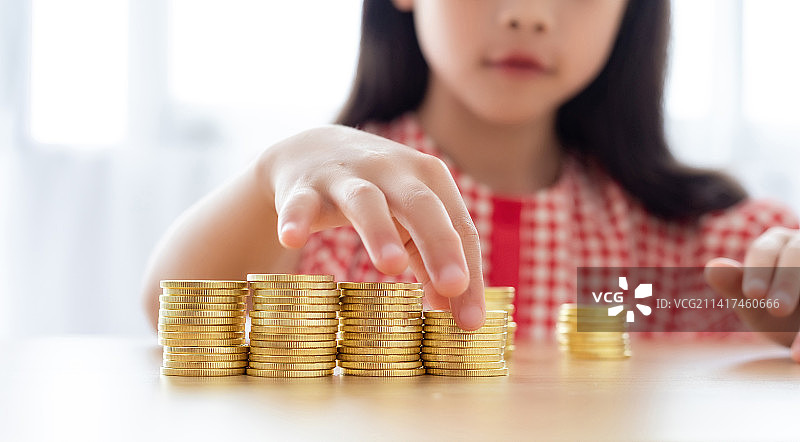 一个中国小女孩在摆放桌面上的金币图片素材