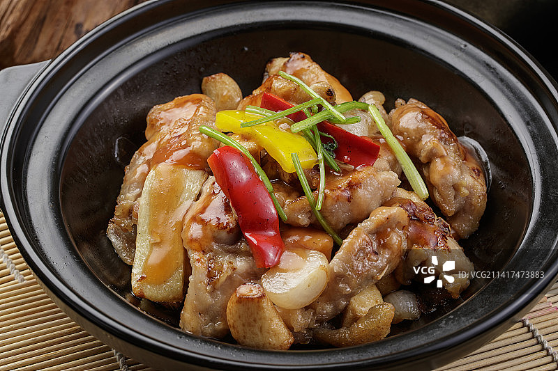 黑色砂锅装的蒜香砂锅鸡腿肉摆放在寿司帘上图片素材