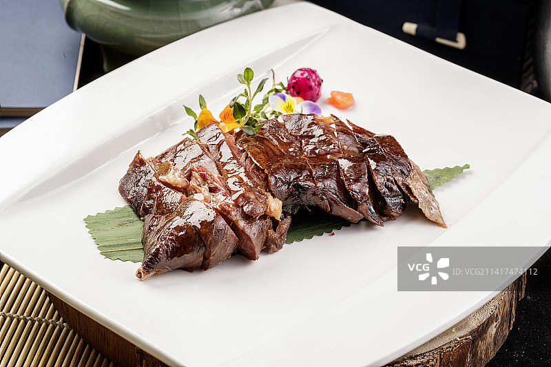 白瓷盘装的苏州酱鸭摆放在寿司帘上图片素材