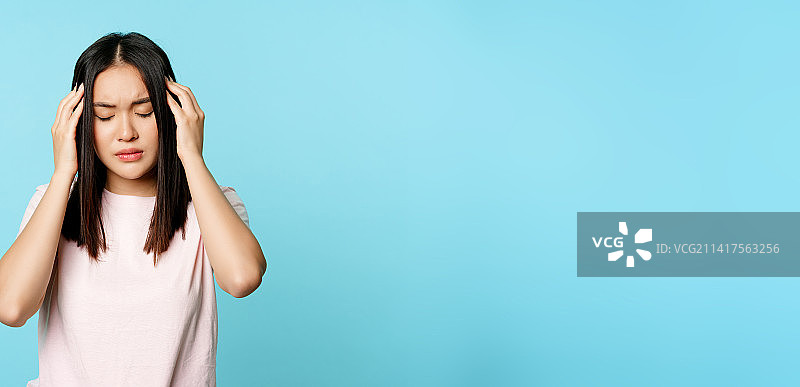 头痛的亚洲小女孩正在按摩头部图片素材