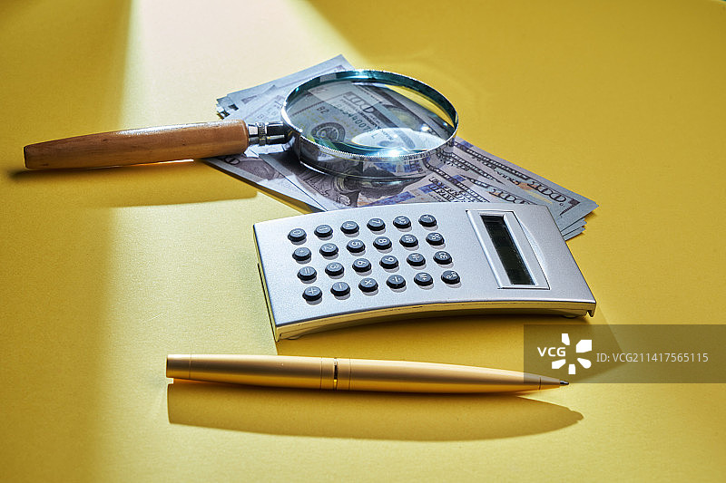 美元纸币上的计算器、笔和放大镜，马来西亚图片素材