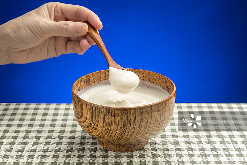 女性手用勺子盛酸奶特写格子桌布背景图片素材
