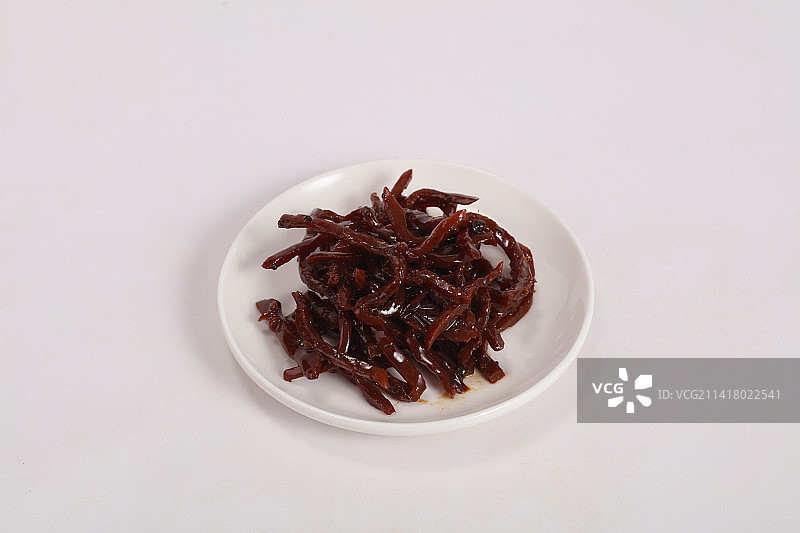 白色瓷盘里的麻辣小咸菜，在白色背景上图片素材