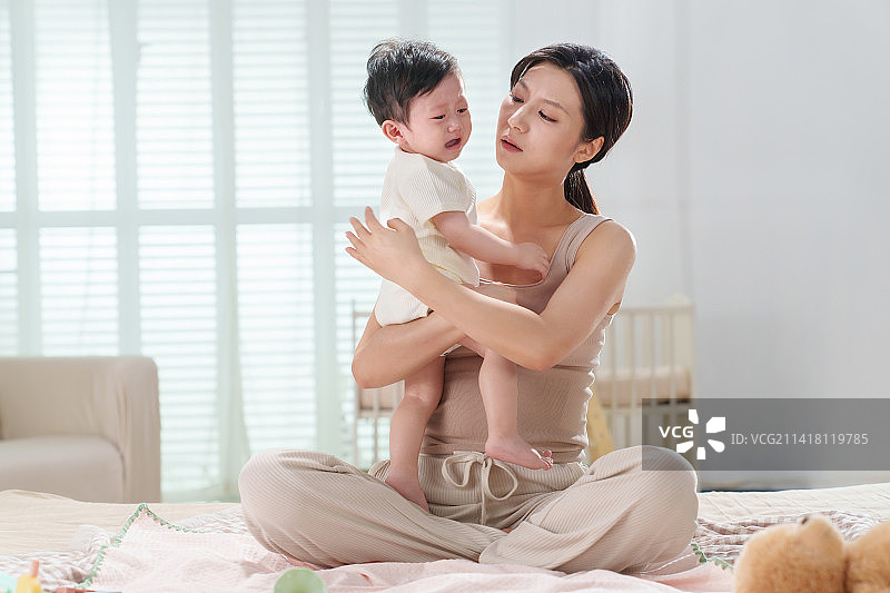 年轻妈妈安抚哭闹的宝宝图片素材