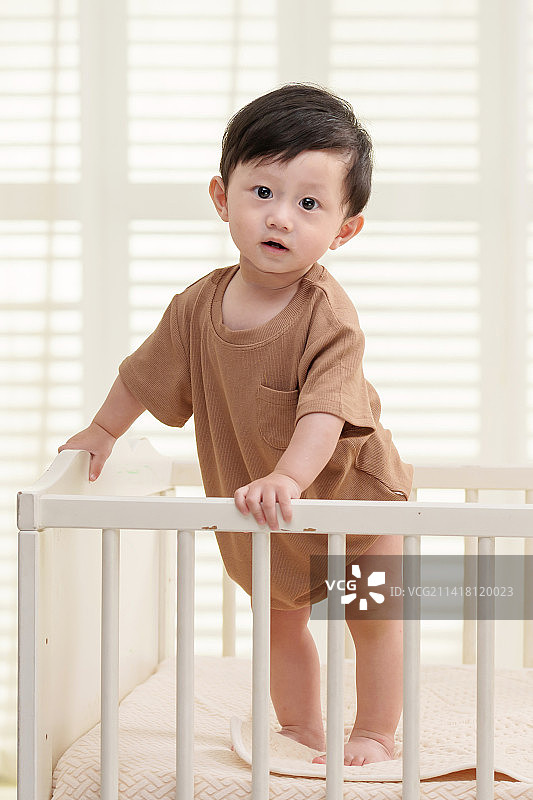 可爱宝宝在婴儿床上玩耍图片素材