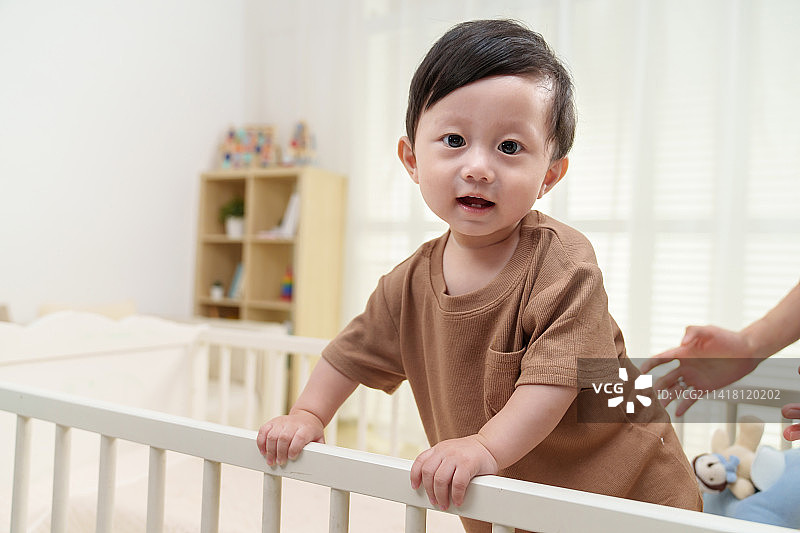 可爱宝宝在婴儿床上玩耍图片素材
