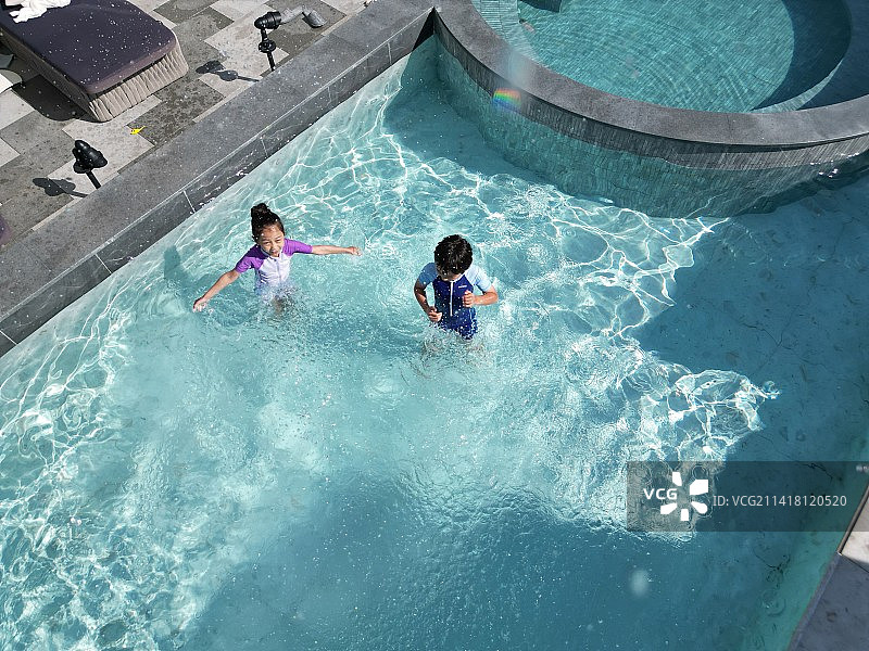 快乐的东方儿童在泳池里戏水图片素材