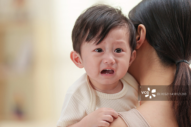 年轻妈妈抱着哭闹的宝宝图片素材