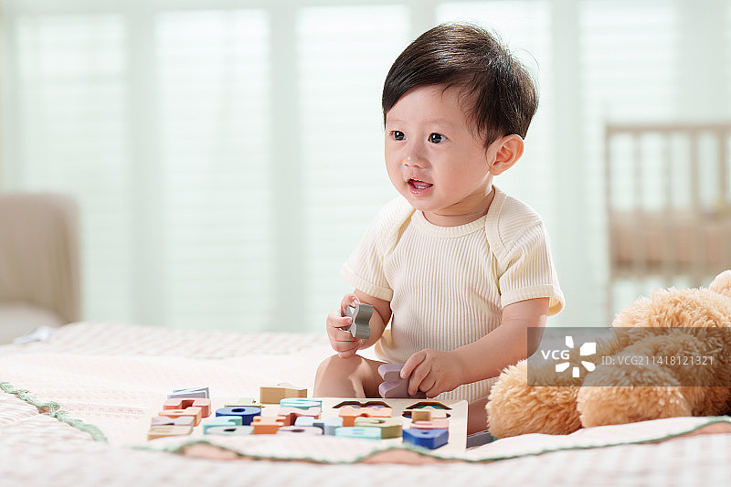 可爱的宝宝坐在床上玩耍图片素材