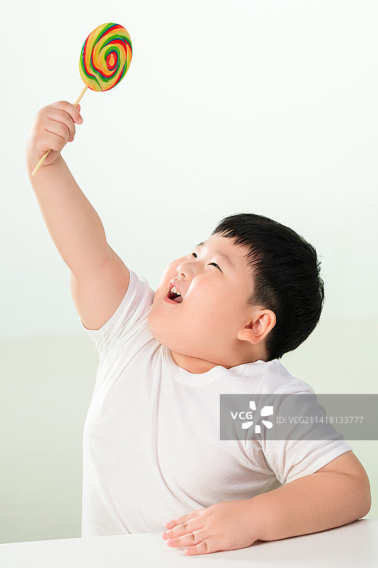 可爱的肥胖小男孩拿着棒棒糖图片素材