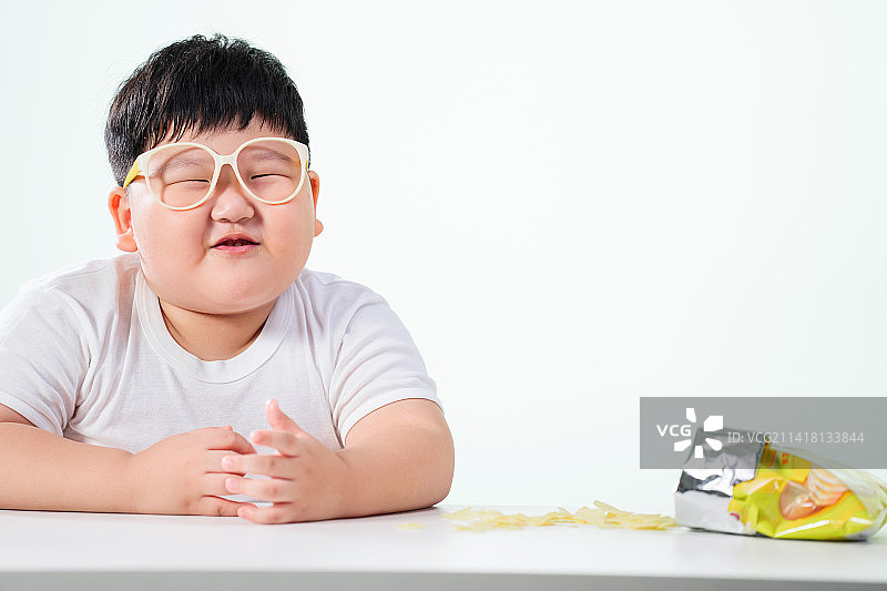 可爱的肥胖小男孩吃薯片图片素材