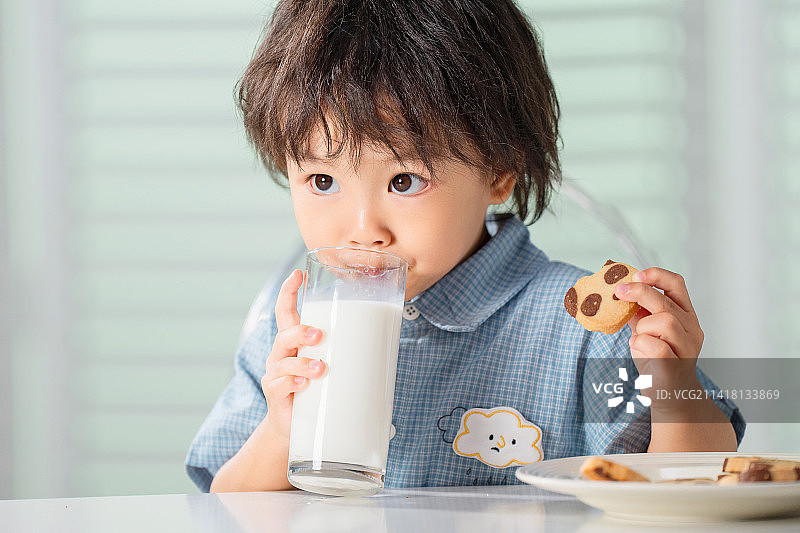 可爱的小男孩吃饼干喝牛奶图片素材