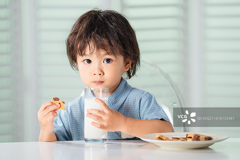 可爱的小男孩吃饼干喝牛奶图片素材