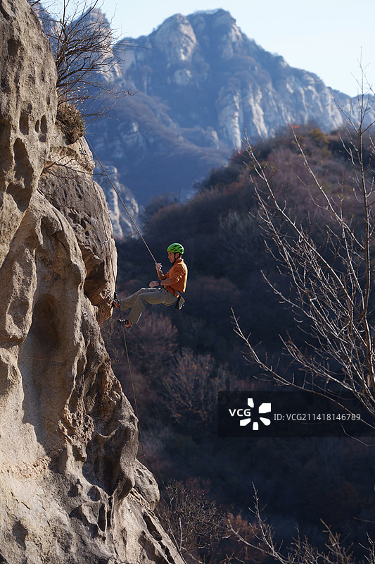 青年男人在悬崖峭壁上攀岩图片素材