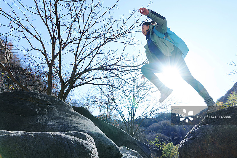 徒步旅行的青年女人跨过石涧图片素材