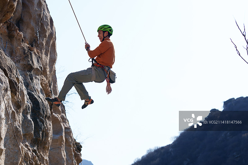 青年男人在悬崖峭壁上攀岩图片素材