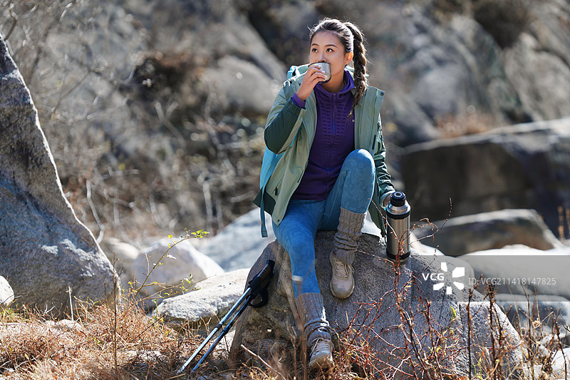 徒步旅行的青年女人坐在石头上休息图片素材