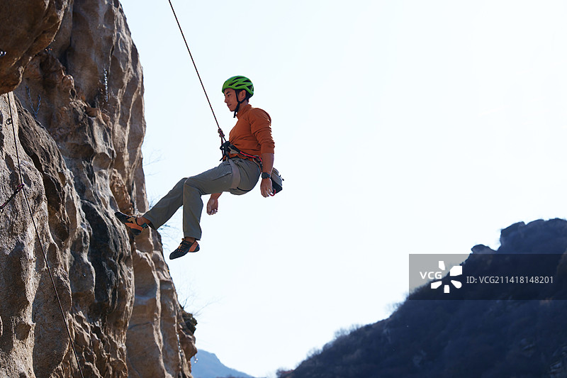 青年男人在悬崖峭壁上攀岩图片素材