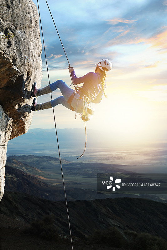 青年女人在悬崖峭壁上攀岩图片素材