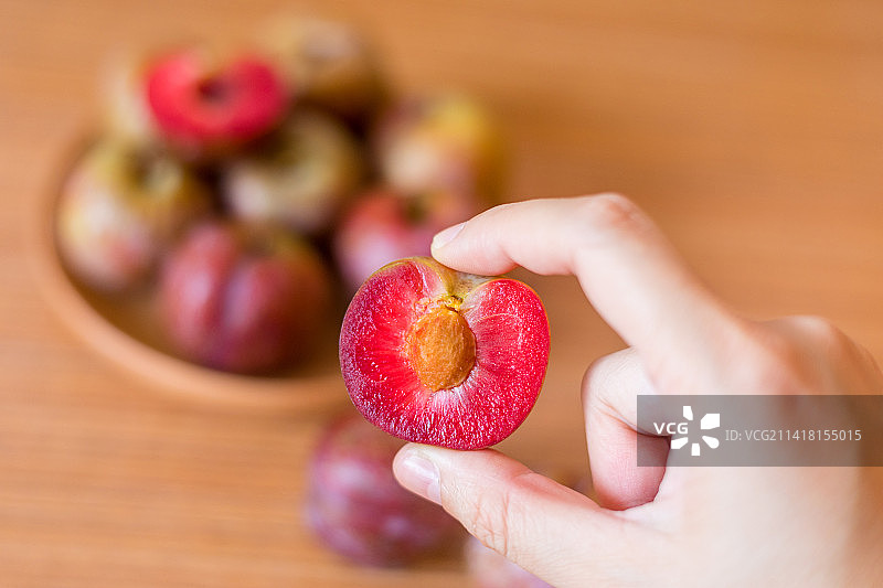 一只手拿着新鲜的广东茂名钱排银妃三华李图片素材