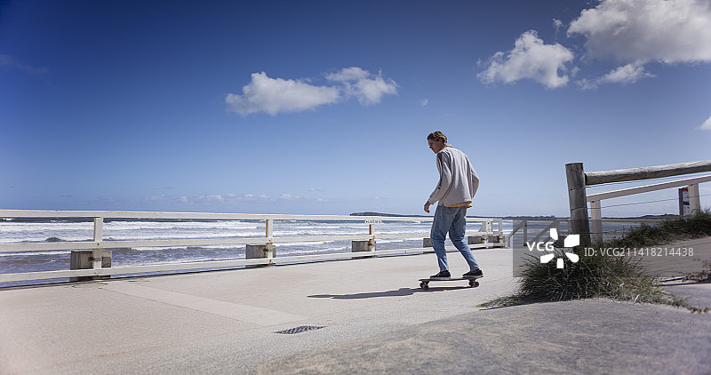 滑板运动员在海边长廊上骑着巡洋舰滑板图片素材