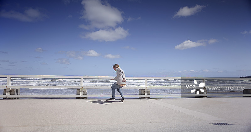 滑板运动员在海边长廊上骑着巡洋舰滑板图片素材