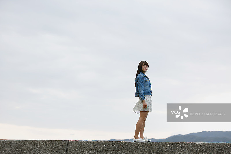 站在海上堤坝上的年轻日本女人图片素材