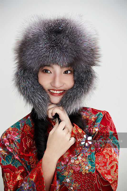 白色背景下穿中国传统服饰头戴绒帽的少女图片素材