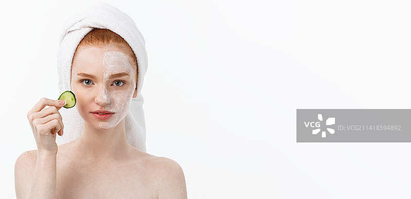 年轻女子戴口罩手持黄瓜片，白色背景图片素材