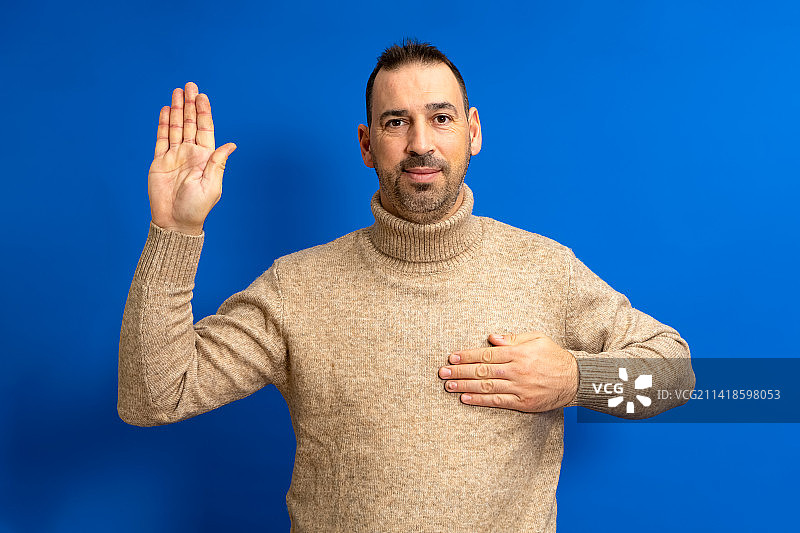 在蓝色背景前做手势的男人肖像图片素材