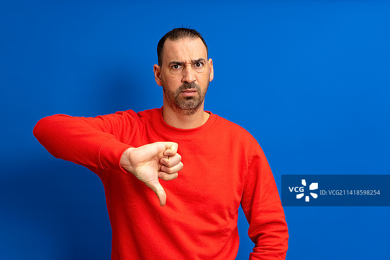 在蓝色背景前做手势的男人肖像图片素材