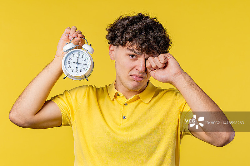 被闹钟吵醒的困倦男人图片素材